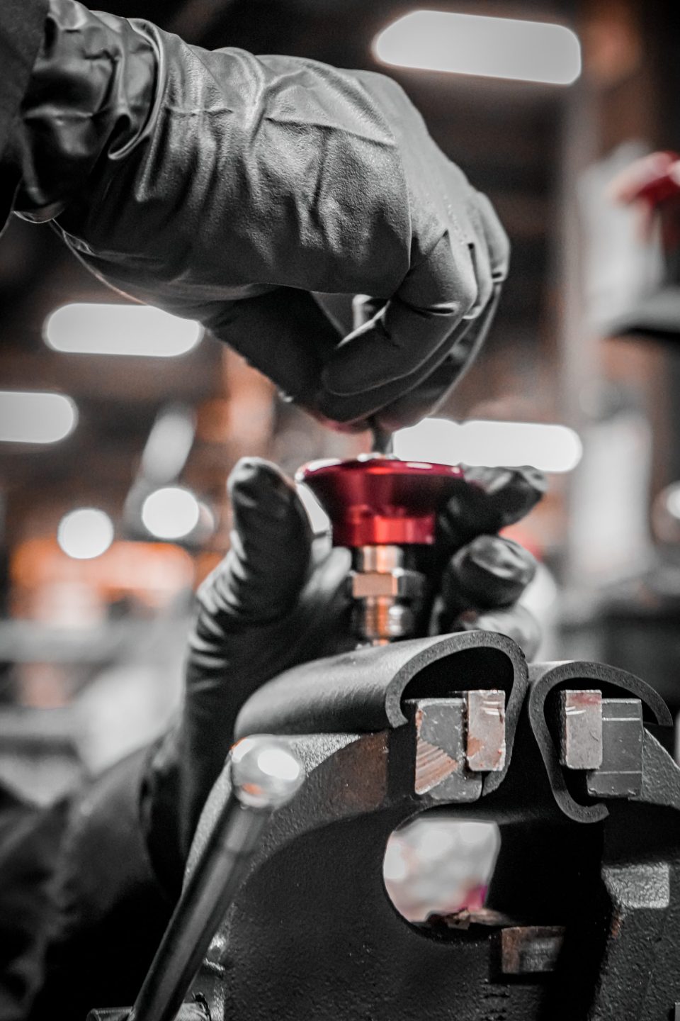 Gloved hands assembling a red part at the Atlantis factory in Laval