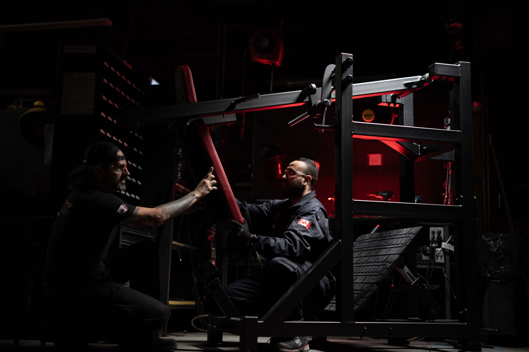 Two Atlantis builders adjust the arm of a plate-loaded machine in the Laval factory